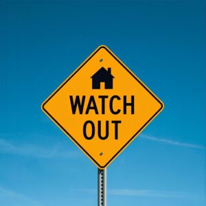 Real estate contract on a desk divided between a house model and a gavel, symbolizing the boundary between real estate agents and lawyers.